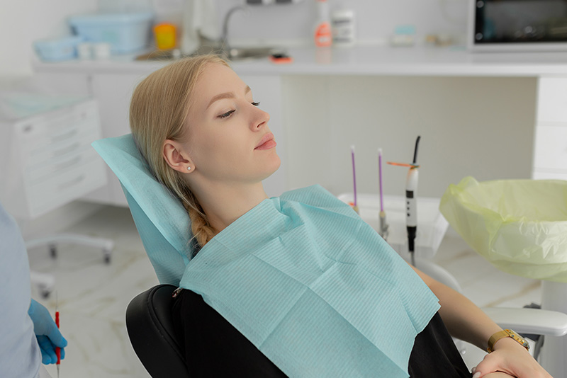 Portrait of a woman sitting at the dental chair on the background at the dental office.