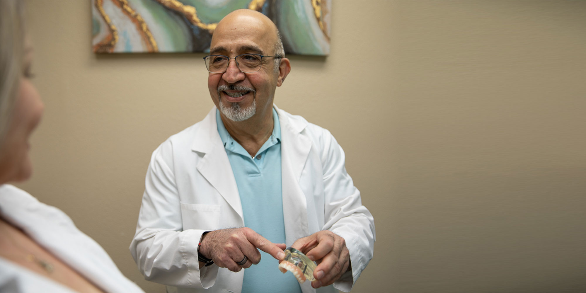 Doctor showing patient dental implant model within the dental practice